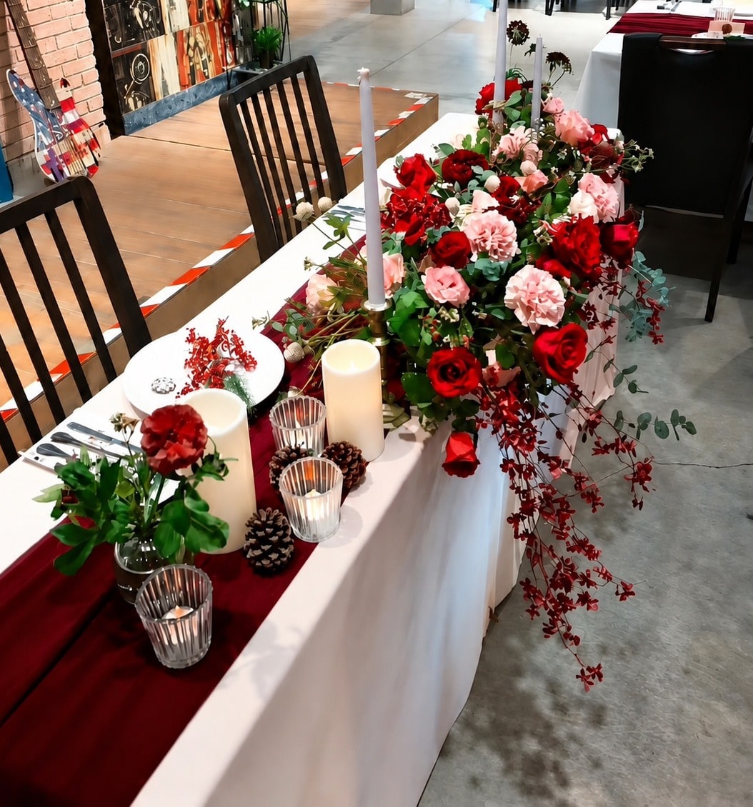 婚禮主桌以紅玫瑰與康乃馨大型花藝裝飾,搭配酒紅桌旗與白色蠟燭